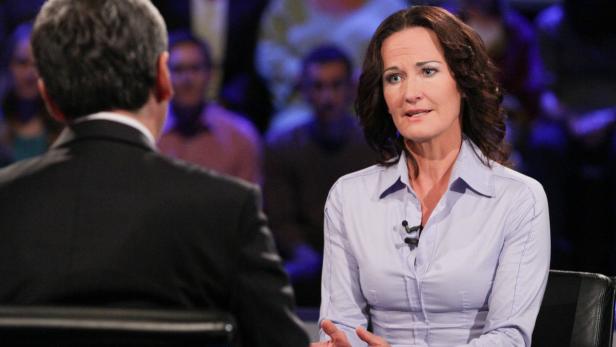 Eine Frau spricht während einer Podiumsdiskussion mit einem Mann.