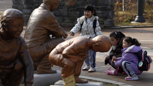 Eine Gruppe von Mädchen betrachtet Bronzestatuen in einem Park.