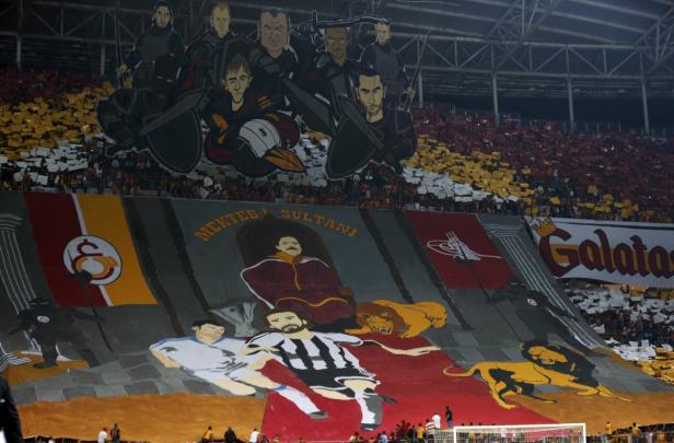 Ein großes Tifo-Banner im Stadion mit Comicfiguren und dem Schriftzug „Mekteb-i Sultani“.
