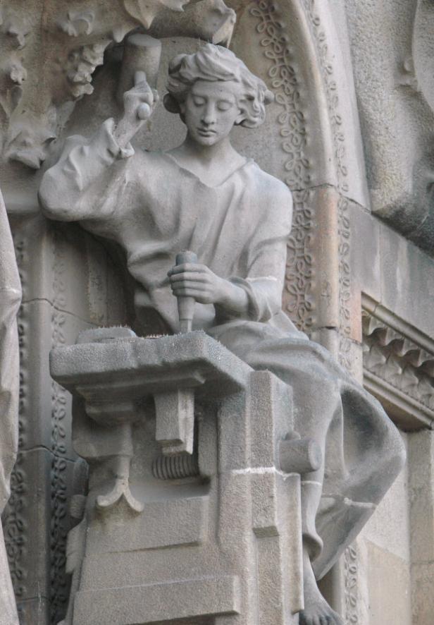 Eine Steinstatue eines Handwerkers bei der Arbeit mit Hammer und Meißel.