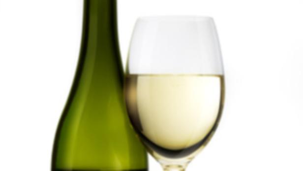 Eine grüne Weinflasche und ein Glas Weißwein vor einem weißen Hintergrund.