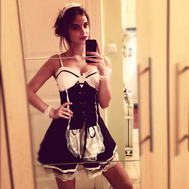 Eine junge Frau macht ein Selfie im Spiegel, verkleidet als Dienstmädchen.