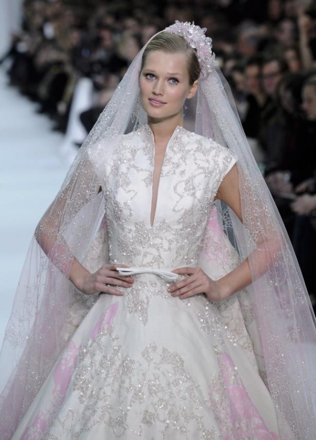 Eine Frau in einem weißen, mit Pailletten besetzten Brautkleid und Schleier auf dem Laufsteg.
