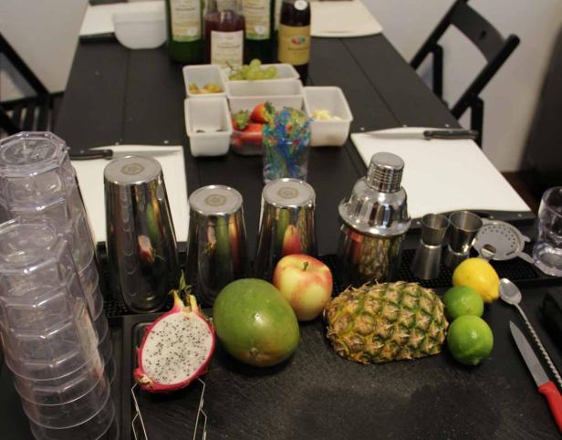 Zutaten und Barwerkzeug für die Zubereitung von Cocktails auf einem Tisch.