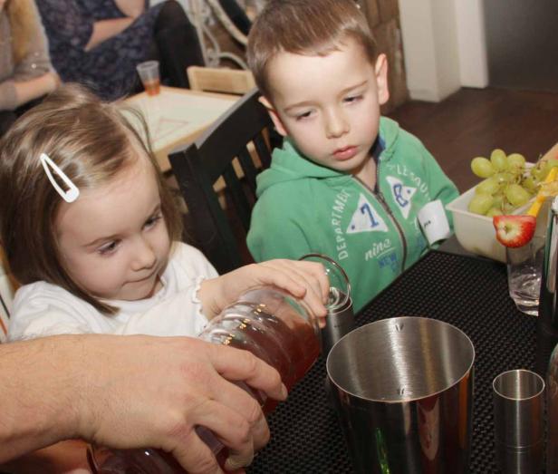 Ein Mädchen und ein Junge beobachten, wie ein Getränk in einen Shaker gegossen wird.
