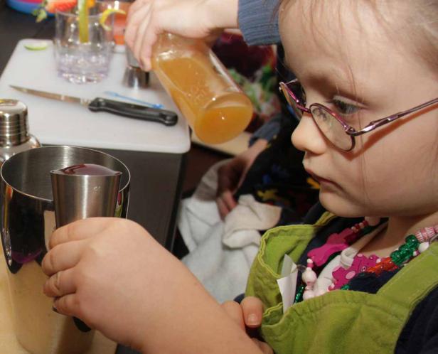 Ein Mädchen mit Brille mixt einen Cocktail.
