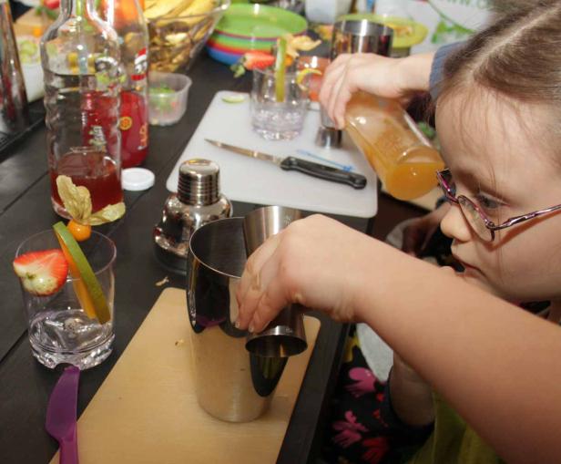 Ein Mädchen mixt einen Cocktail mit Früchten und Säften.
