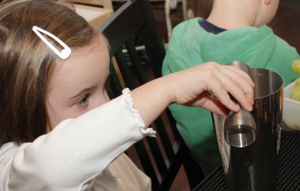 Ein Mädchen mit Haarspange hantiert mit einem Cocktailshaker.