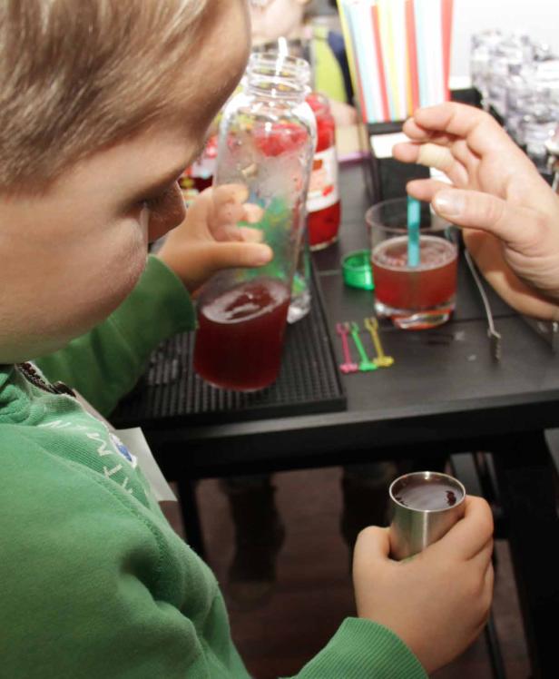 Ein Kind gießt ein rotes Getränk in ein Glas.