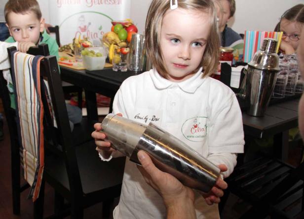 Ein junges Mädchen hält einen Cocktailshaker in ihren Händen.