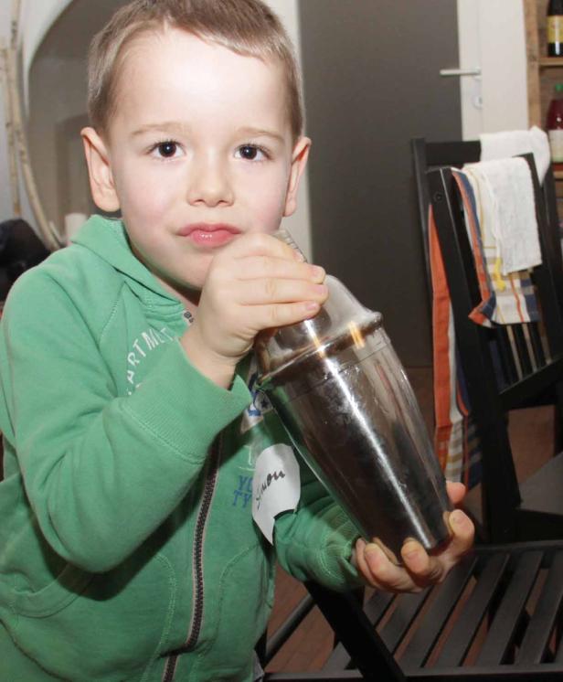 Ein kleiner Junge hält einen Cocktailshaker in seinen Händen.