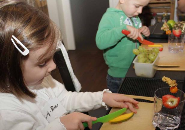 Zwei Kinder bereiten Obstspieße zu.