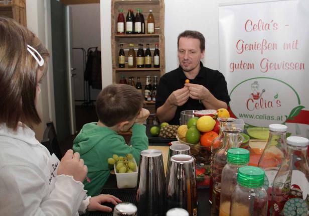 Ein Mann erklärt Kindern die Zubereitung von Getränken mit frischen Früchten.
