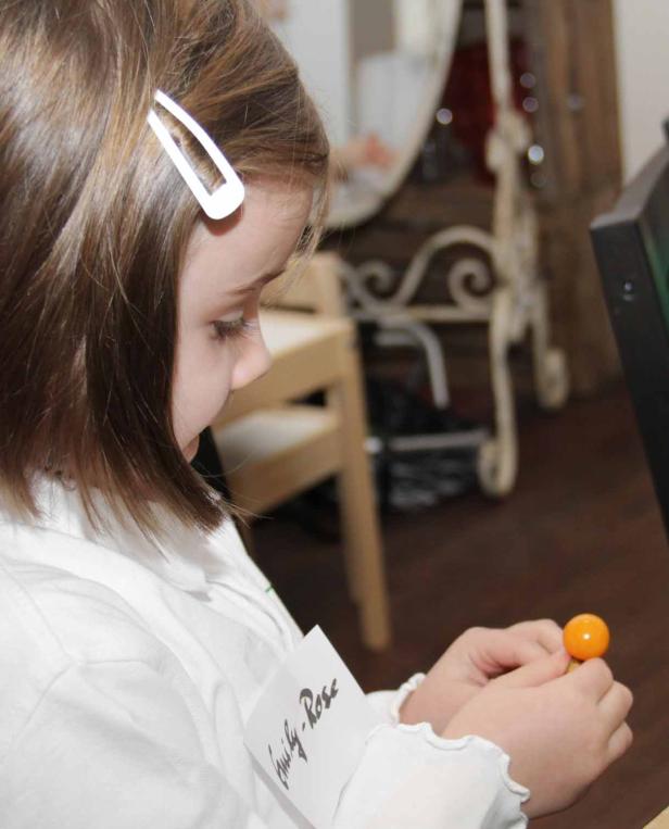 Ein Mädchen namens Emily-Rose betrachtet einen orangefarbenen Gegenstand in ihren Händen.