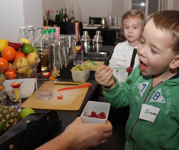 Ein Junge namens Simon isst eine Himbeere an einer Bar, an der Cocktails zubereitet werden.