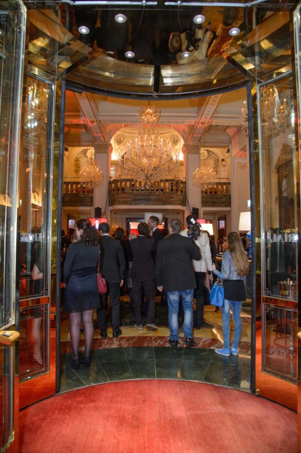Gäste betreten einen opulenten Ballsaal durch eine Drehtür.