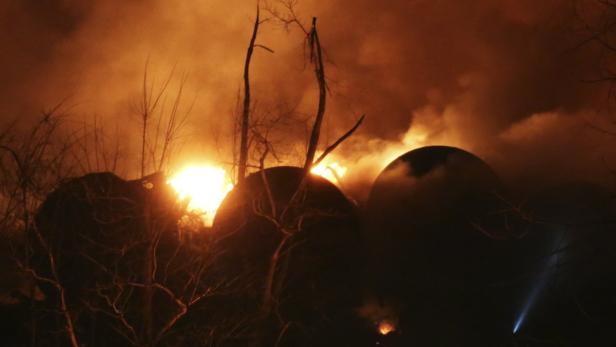 Ein Feuer brennt im Hintergrund von dunklen, kugelförmigen Objekten.