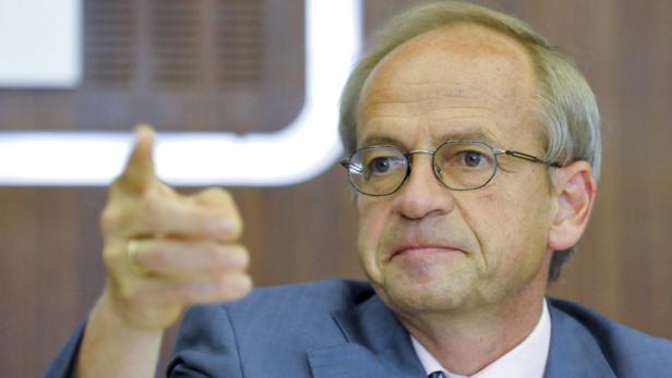 Ein Mann mit Brille und Anzug gestikuliert mit dem Finger.