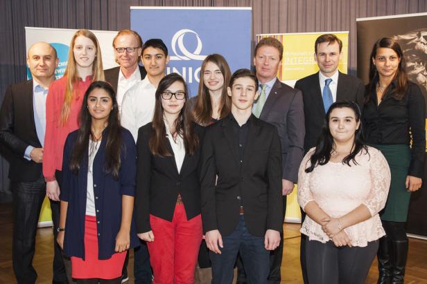 Eine Gruppe von Jugendlichen und Erwachsenen posiert für ein Gruppenfoto vor Bannern.