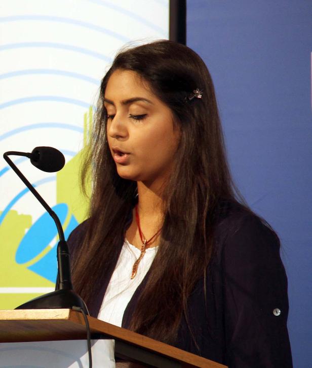 Eine junge Frau spricht an einem Rednerpult vor einem Mikrofon.