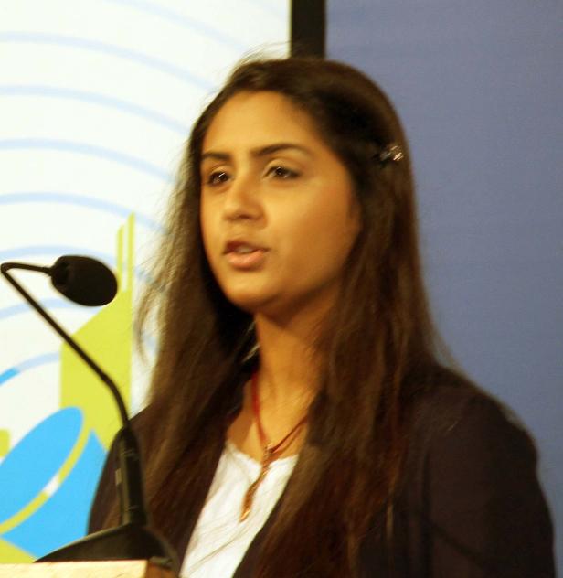 Eine Frau spricht bei einer Veranstaltung an einem Mikrofon.