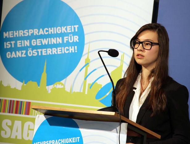 Eine junge Frau spricht bei einer Veranstaltung zum Thema Mehrsprachigkeit in Österreich.