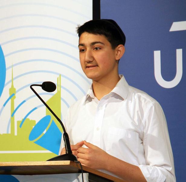 Ein junger Mann hält eine Rede an einem Rednerpult.