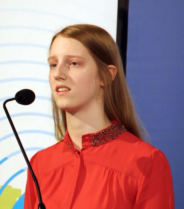Eine junge Frau spricht an einem Mikrofon.