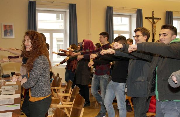 Eine Gruppe junger Leute macht Dehnübungen in einem Raum.