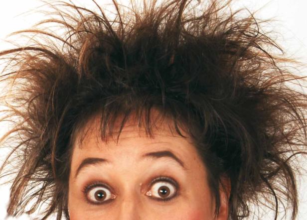 Eine Frau mit wilder Frisur und großen Augen blickt in die Kamera.