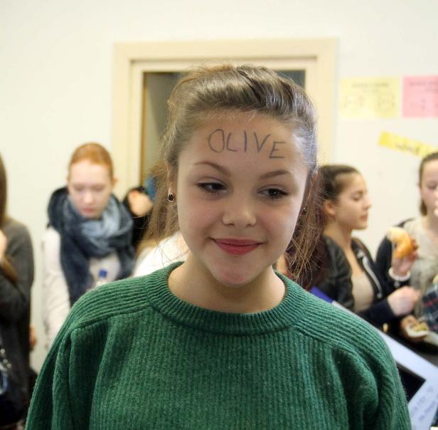 Ein junges Mädchen mit dem Wort „OLIVE“ auf der Stirn geschrieben.