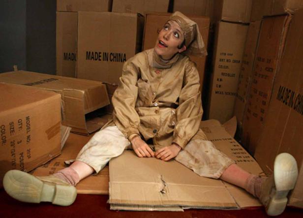 Eine Person in Arbeitskleidung sitzt inmitten von Kartons mit der Aufschrift „Made in China“.