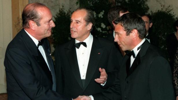 Jacques Chirac schüttelt die Hand eines Mannes in Anwesenheit einer weiteren Person.