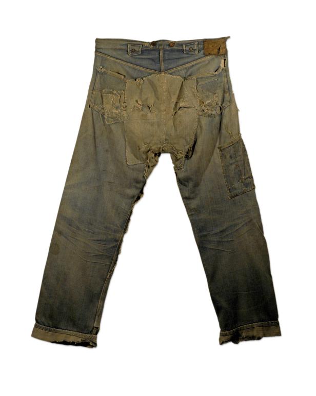 Eine stark abgenutzte und geflickte Jeanshose vor einem weißen Hintergrund.