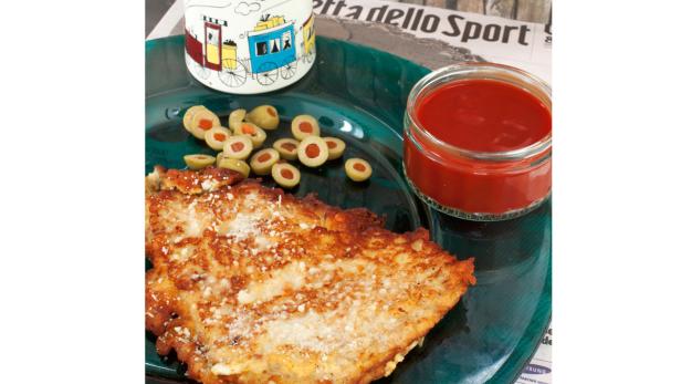 Ein Teller mit Kartoffelpuffer, Oliven und einem Glas Tomatensauce.