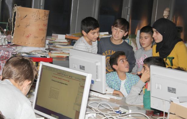 Eine Gruppe von Schülern arbeitet gemeinsam an Computern in einem Klassenzimmer.