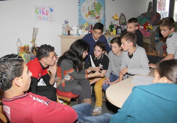 Eine Frau spricht mit einer Gruppe von Jugendlichen in einem Klassenzimmer.