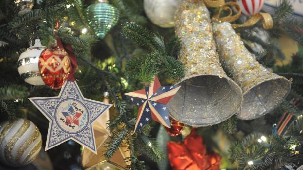 Ein Weihnachtsbaum ist mit Sternen, Kugeln und glitzernden Glocken geschmückt.