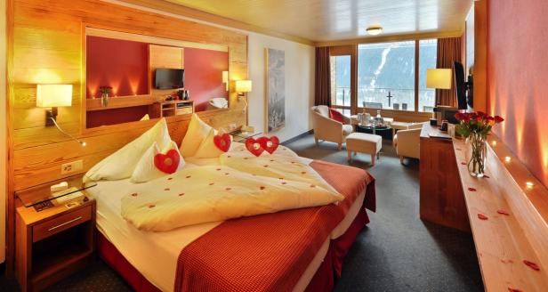 Ein Hotelzimmer ist mit Rosenblättern und Herzdekorationen romantisch hergerichtet.