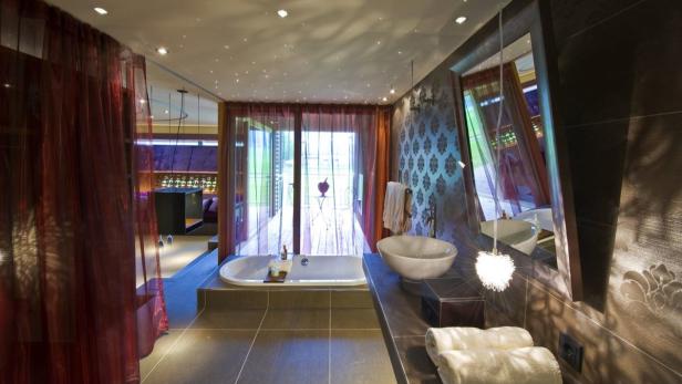 Ein luxuriöses Badezimmer mit Badewanne, Waschbecken und roten Vorhängen.