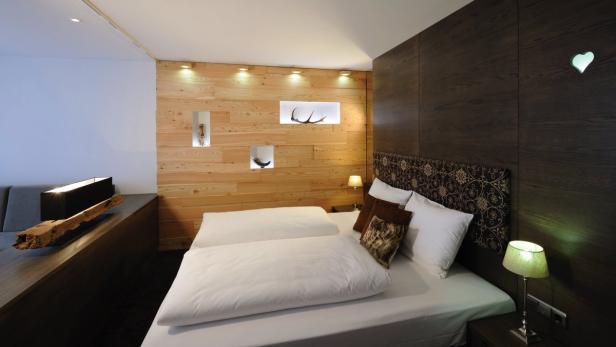 Ein Schlafzimmer mit Holzwand und einem Doppelbett mit weißen Kissen und Decken.