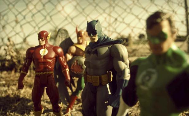 Actionfiguren der Justice League stehen vor einem Zaun.
