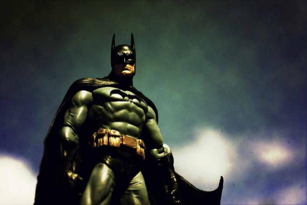 Eine Batman-Figur steht vor einem bewölkten Himmel.