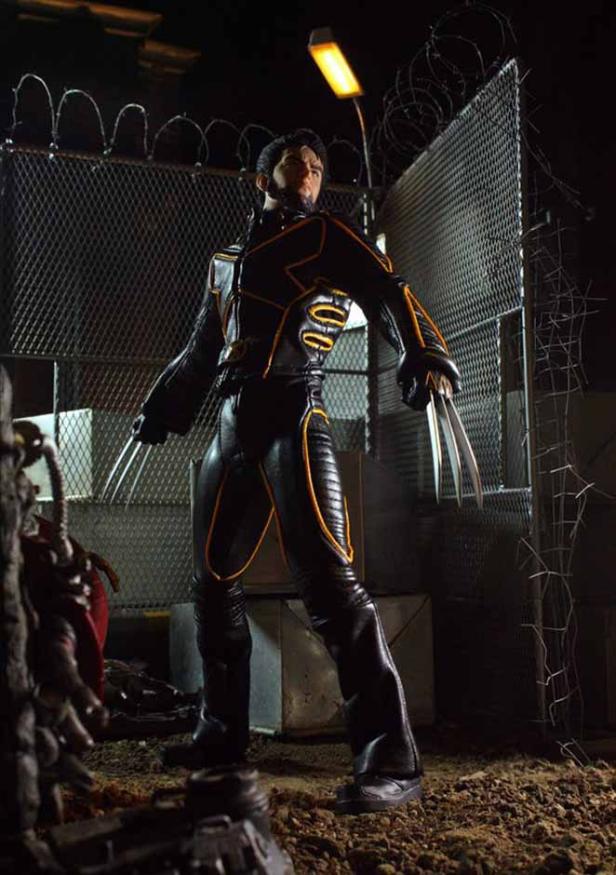 Wolverine steht vor einem Zaun mit Stacheldraht und zeigt seine Krallen.