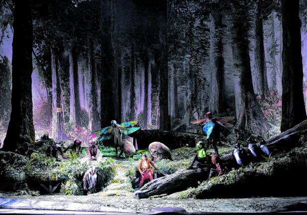 Eine Theaterszene mit Darstellern in Kostümen in einem dunklen Wald.