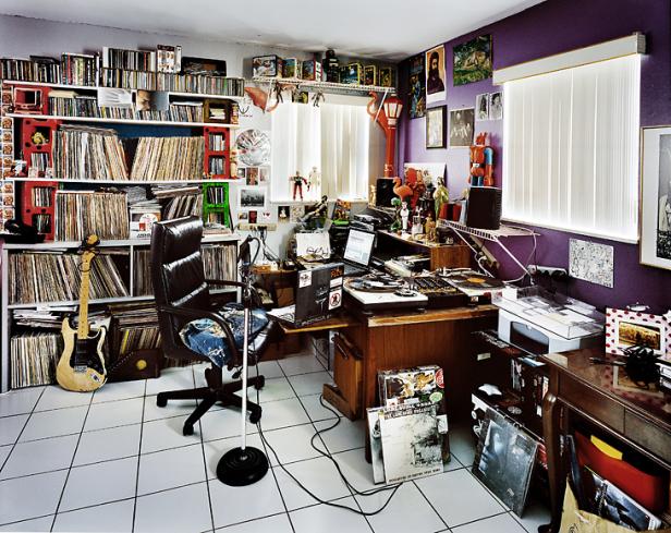 Ein Arbeitszimmer mit Schreibtisch, Plattenspieler, Gitarre und vielen Schallplattenregalen.