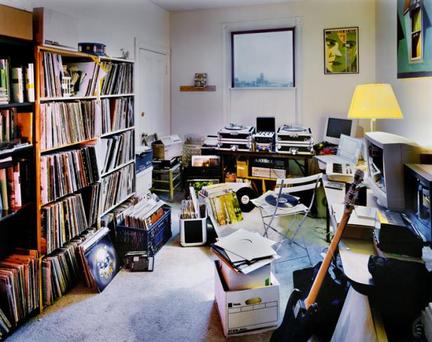 Ein Zimmer voller Schallplatten, Plattenspieler, Computer und einer Gitarre.