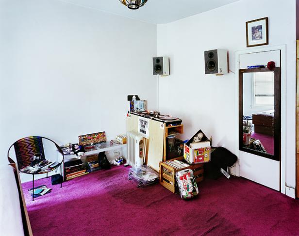 Ein Zimmer mit lila Teppich, Plattenspieler, Lautsprechern und Schallplattenkisten.