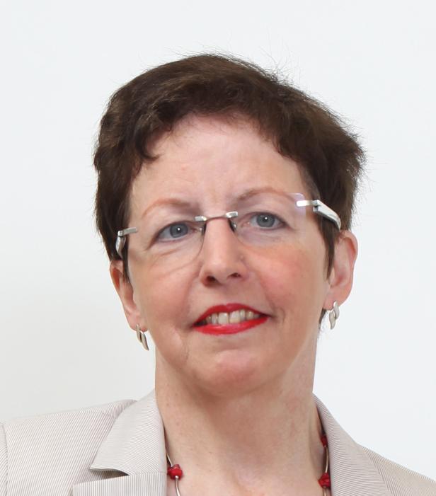 Eine Frau mit Brille, rotem Lippenstift und kurzem braunem Haar lächelt.