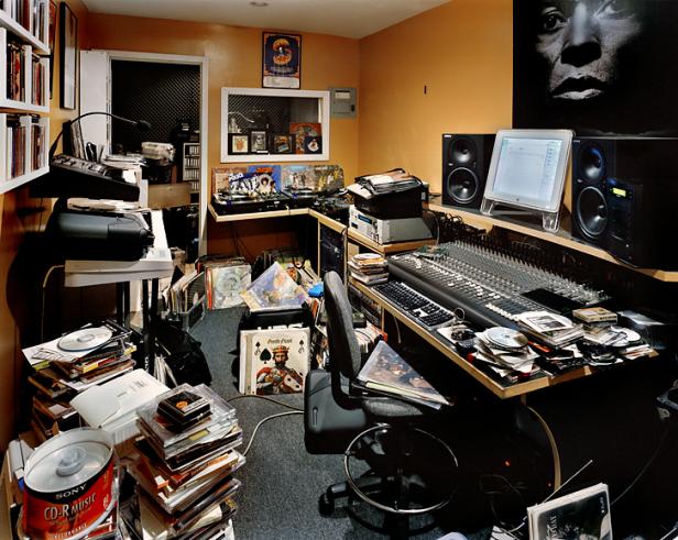Ein unordentliches Musikstudio mit Mischpult, Computern, Schallplatten und CDs.